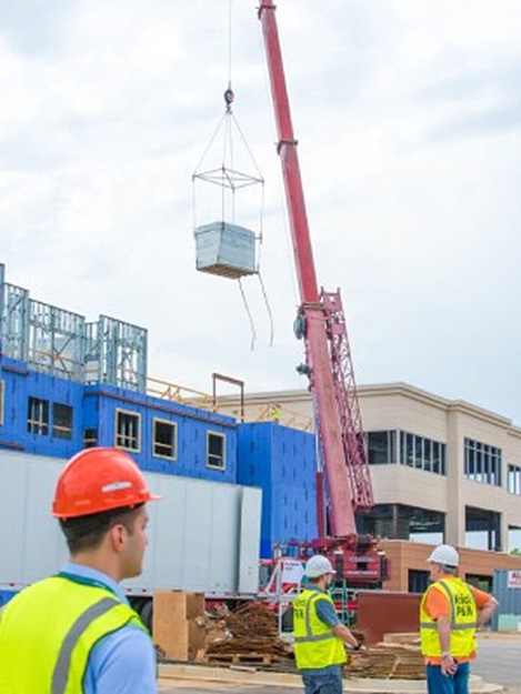 SurePods bathroom pod being transported by crane at a construction site, highlighting innovation in prefabricated modules.