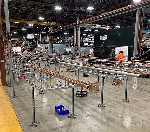 Workers assembling MEP racks at a prefabrication facility, streamlining the construction process for healthcare facilities.